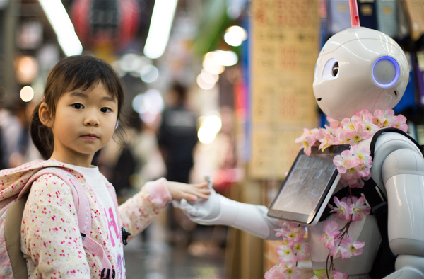 Pepper, a social robot, shakes hands with a little girl at Kuromon Ichiba Market, Osaka, Japan. PHOTOGRAPH: ANDY KELLY / UNSPLASH